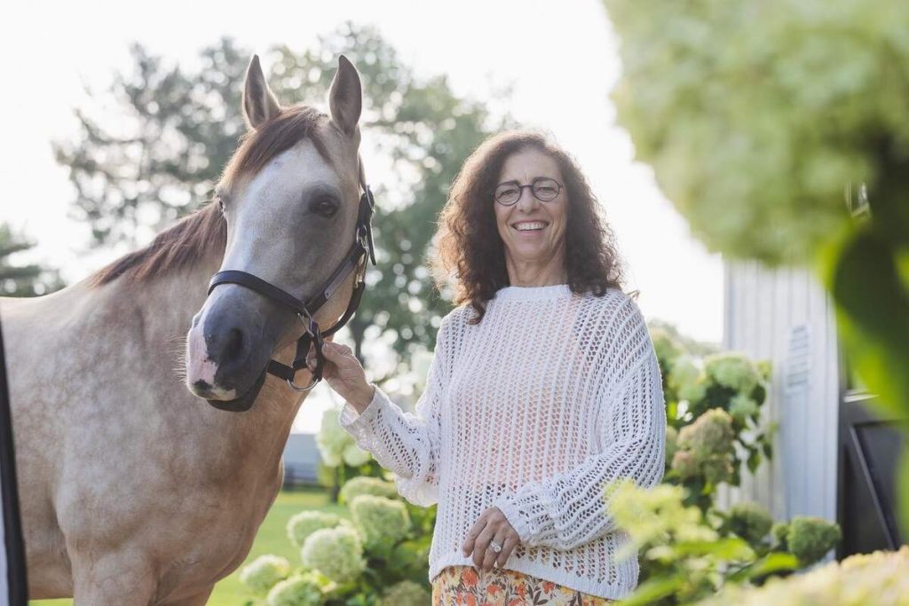 Woman holding on to halter of horse.