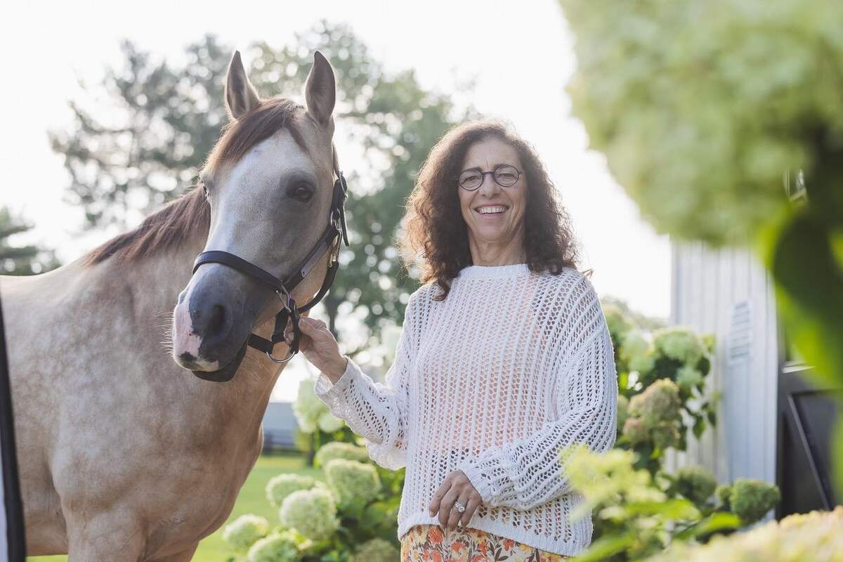 Woman holding on to halter of horse.